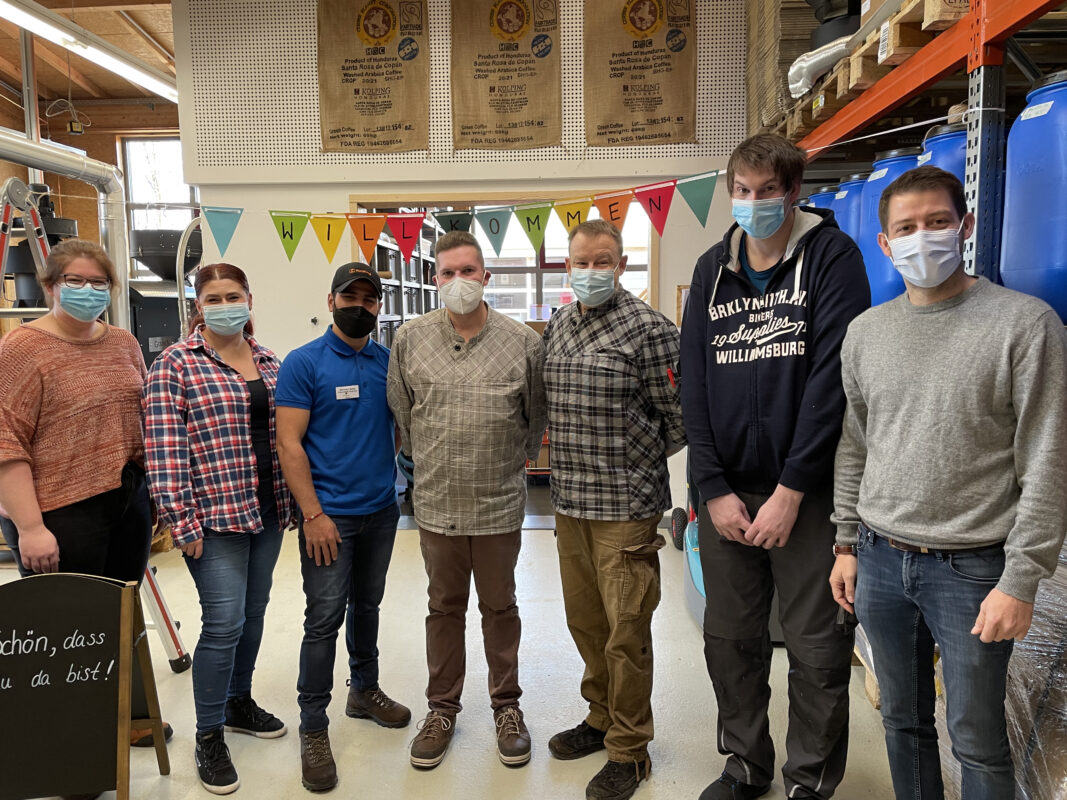 Die Mitarbeitenden der Röstwerkstatt begrüßen den Freiwilligen Damian.
